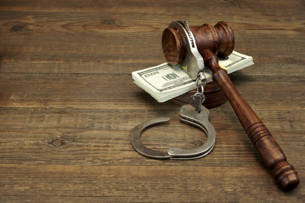 Cash, Real Handcuffs And Judge Gavel On Rough Wood Background